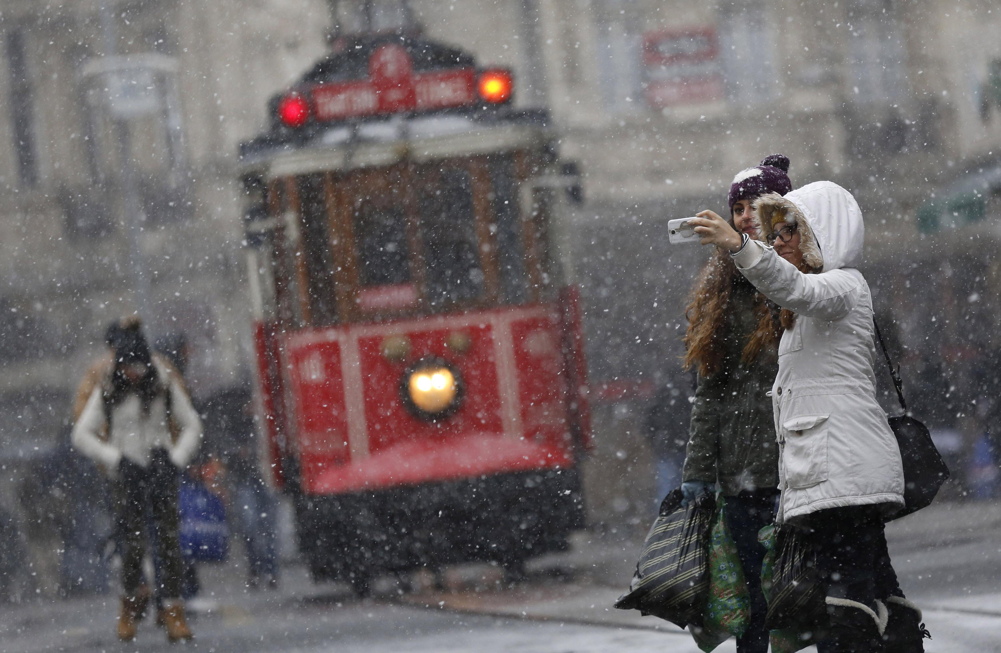 Pedestrians, with a vintage tram in the background, take a "selfie" as snow falls at the main shopping street of Istiklal in central Istanbul, in this January 6, 2015 file photo. REUTERS/Murad Sezer/Files (TURKEY - Tags: ENVIRONMENT SOCIETY) ATTENTION EDITORS - THIS PICTURE IS PART OF THE PACKAGE "THE SELFIE PHENOMENON". TO FIND ALL 19 IMAGES SEARCH 'SELFIE'